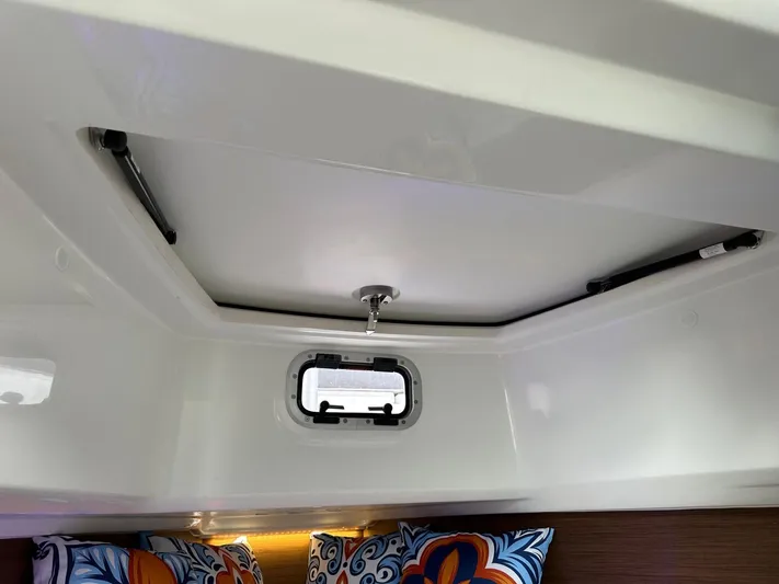 Jebang Yacht Photos Pics 2023 Jeanneau Leader 9.0 CC cabin interior with window and colorful cushions.