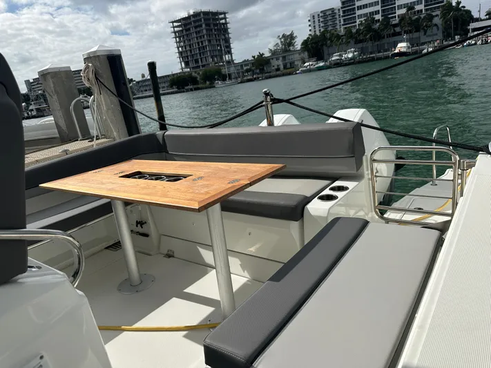 Jebang Yacht Photos Pics 2023 Jeanneau Leader 9.0 CC boat interior with seating and table, docked by the water.
