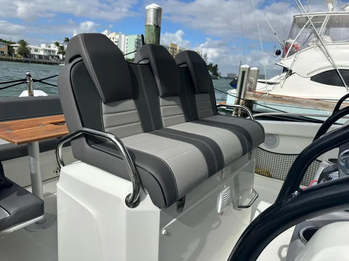 Jebang Yacht Photos Pics 2023 Jeanneau Leader 9.0 CC boat seating with gray upholstery, docked in a marina.