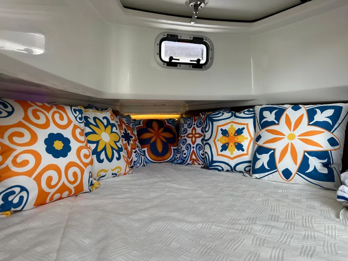 Jebang Yacht Photos Pics 2023 Jeanneau Leader 9.0 CC cabin with colorful patterned cushions and a small window.