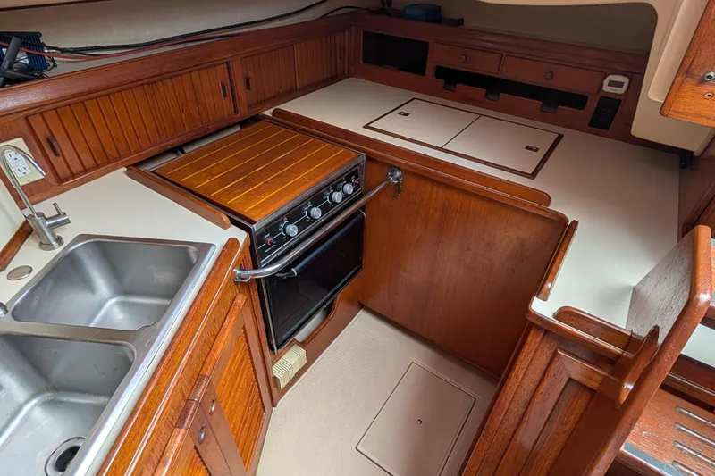 Lone Star Yacht Photos Pics 1988 Island Packet 38 yacht kitchen with wooden cabinetry, stove, and double sink.