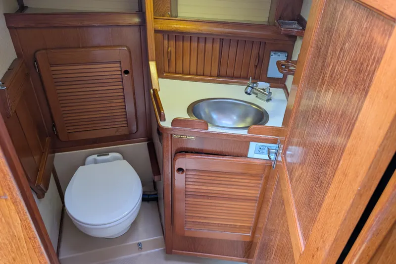 Lone Star Yacht Photos Pics 1988 Island Packet 38 yacht bathroom with wooden cabinetry, sink, and toilet.