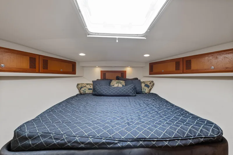  Yacht Photos Pics 2004 Cabo 40 Express cabin with bed, wooden storage, and overhead lighting.