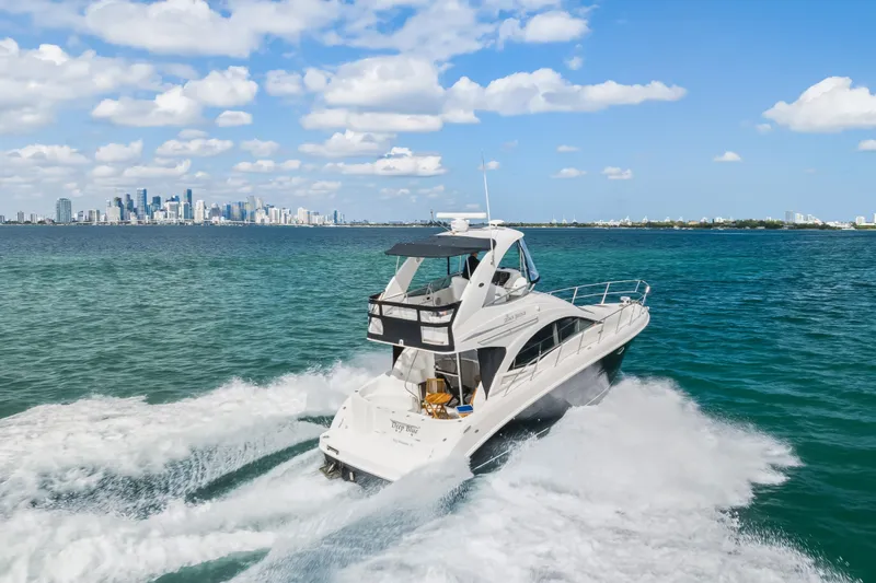 Deep Blue Yacht Photos Pics 2008 Sea Ray 36 Sedan Bridge cruising on blue ocean with city skyline in background.