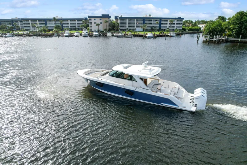  Yacht Photos Pics 2022 Tiara Yachts 48 LS cruising on a scenic waterfront with buildings in the background.