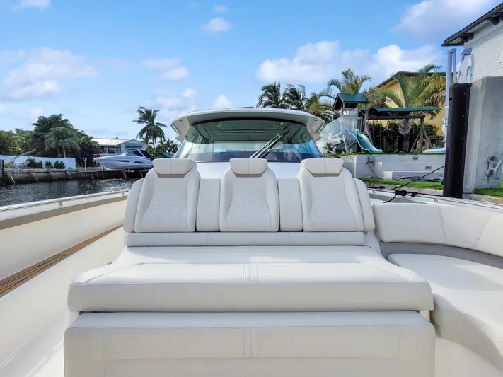  Yacht Photos Pics 2022 Tiara Yachts 48 LS luxury boat with plush seating, docked by palm trees.
