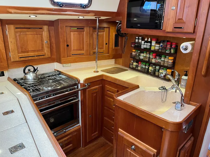 Sapphire Yacht Photos Pics 2014 Tartan 4700 yacht kitchen with wooden cabinetry, stove, sink, and spice rack.