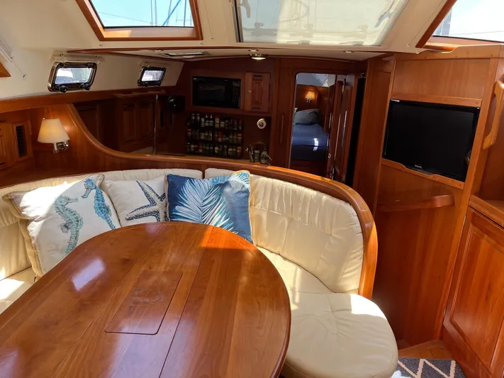Sapphire Yacht Photos Pics Interior of 2014 Tartan 4700 sailboat with wooden dining table and cushioned seating.