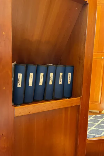Sapphire Yacht Photos Pics Blue binders on a wooden shelf inside a 2014 Tartan 4700 sailboat.