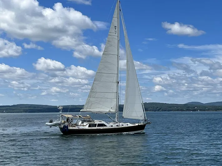 Sapphire Yacht Photos Pics Sailing yacht Tartan 4700 (2014) on a calm sea under a blue sky with clouds.