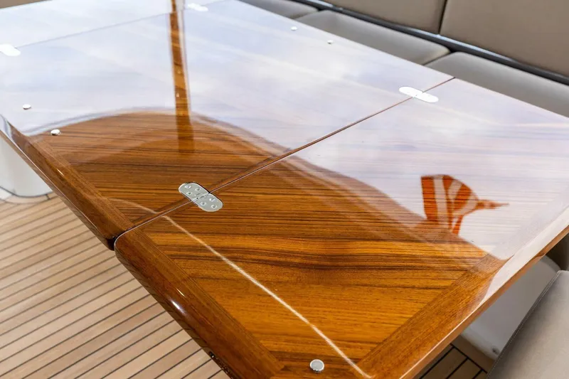Amarula Sun Yacht Photos Pics Polished wooden table on 2024 Princess X80 yacht deck, reflecting sky and flag.