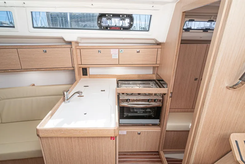 New Sailboat Yacht Photos Pics 2024 Bavaria Cruiser 34 yacht interior kitchen with stove, sink, and wooden cabinetry.