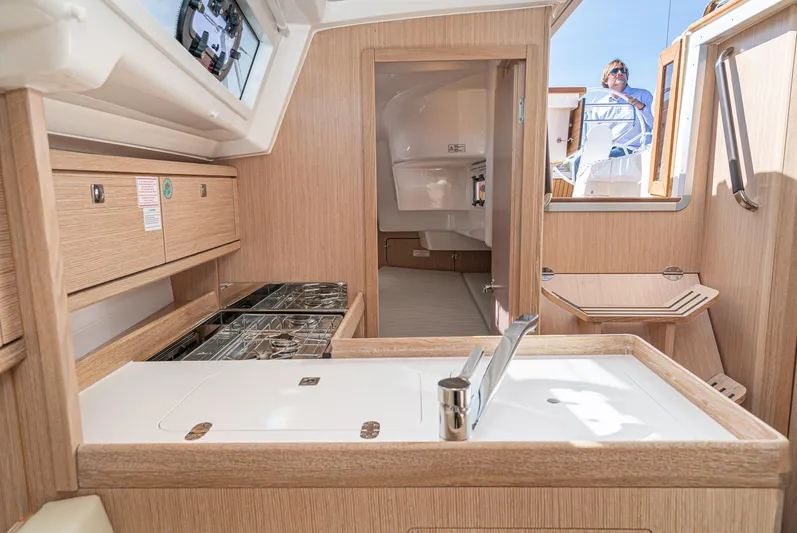 New Sailboat Yacht Photos Pics Modern interior of 2024 Bavaria Cruiser 34 yacht with wooden finishes and compact kitchen.