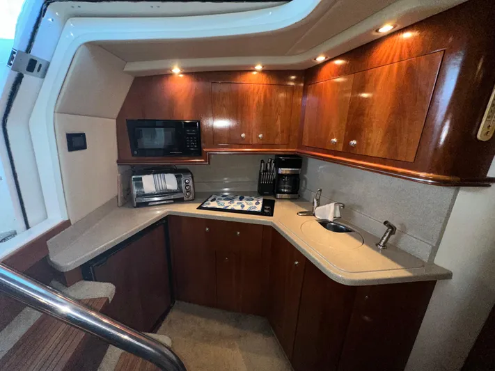  Yacht Photos Pics 2005 Cruisers Yachts 340 Express kitchen with wood cabinets, microwave, and sink.