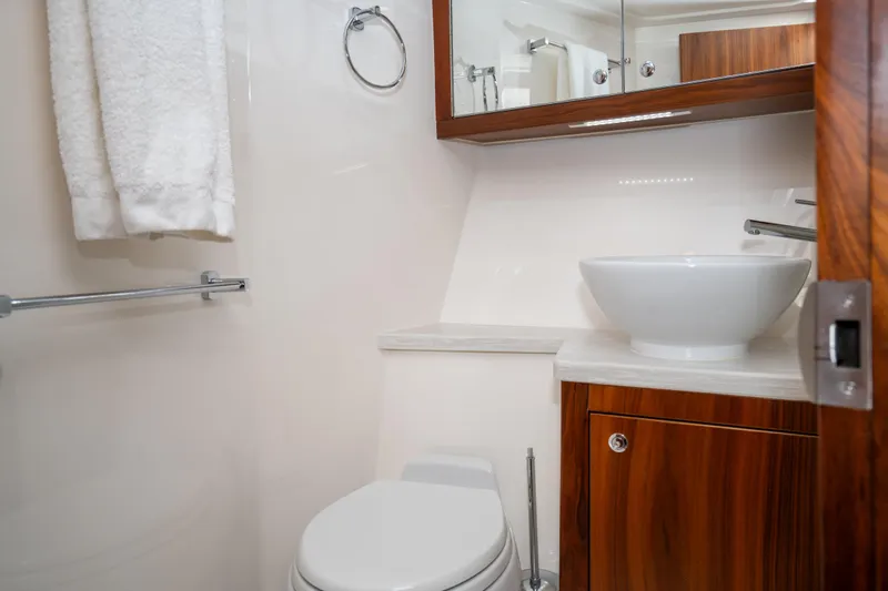  Yacht Photos Pics Luxurious bathroom in 2022 Riviera 445 SUV yacht with modern fixtures and wooden cabinetry.