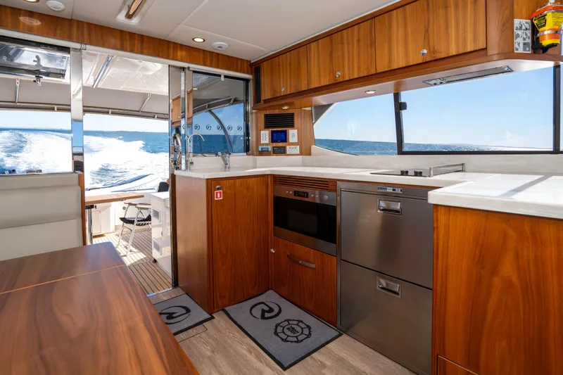  Yacht Photos Pics Luxurious 2022 Riviera 445 SUV yacht interior with modern kitchen and ocean view.