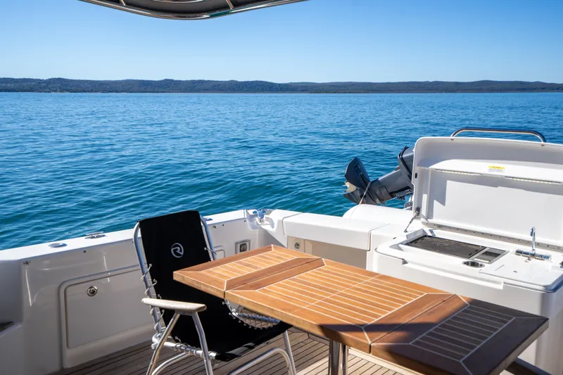  Yacht Photos Pics Riviera 445 SUV 2022 yacht deck with table, chair, and ocean view.