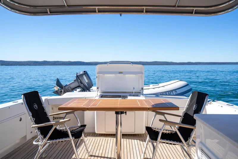  Yacht Photos Pics 2022 Riviera 445 SUV yacht deck with chairs, table, and ocean view.