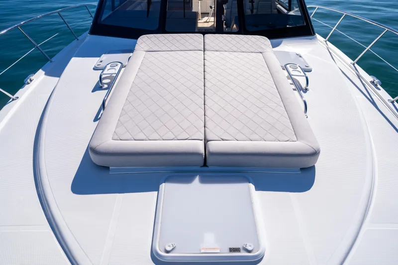  Yacht Photos Pics 2022 Riviera 445 SUV yacht with cushioned sunbed on deck, surrounded by ocean.