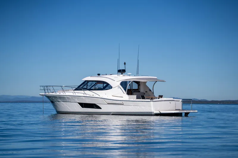  Yacht Photos Pics 2022 Riviera 445 SUV yacht on calm blue water under clear sky.