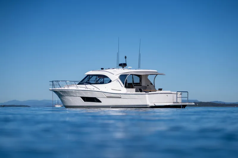  Yacht Photos Pics 2022 Riviera 445 SUV yacht on calm blue water under clear sky.