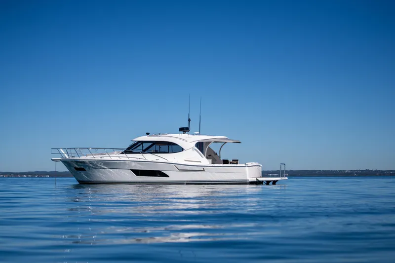  Yacht Photos Pics 2022 Riviera 445 SUV yacht on calm blue water under clear sky.