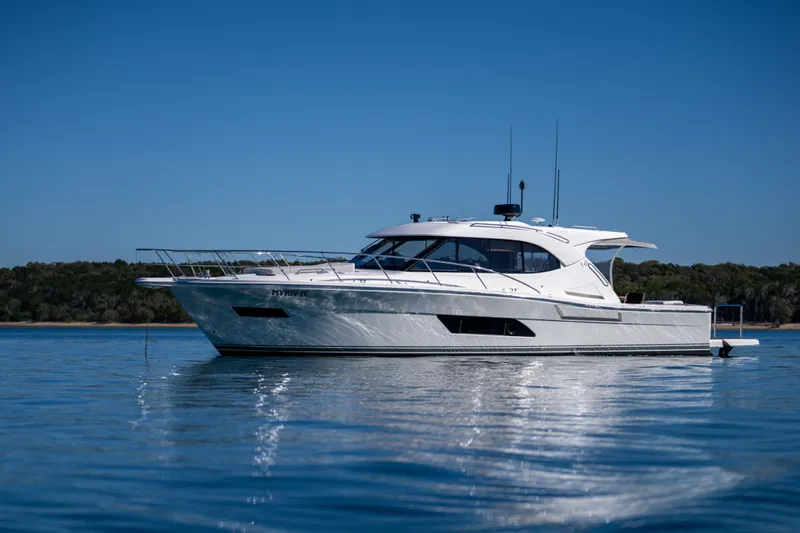  Yacht Photos Pics 2022 Riviera 445 SUV yacht on calm water under clear blue sky.