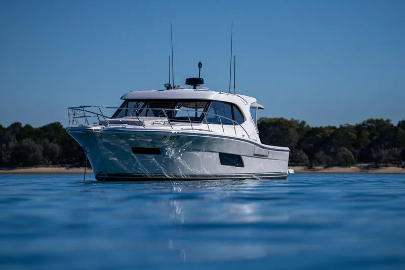  Yacht Photos Pics 2022 Riviera 445 SUV yacht on calm water, with a scenic shoreline backdrop.