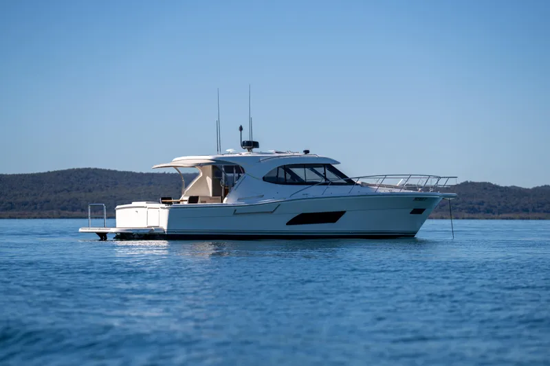  Yacht Photos Pics 2022 Riviera 445 SUV yacht on calm water with scenic background.