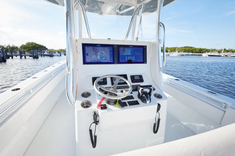  Yacht Photos Pics 2022 Contender 35 ST boat console with navigation screens, steering wheel, and controls on a sunny day.