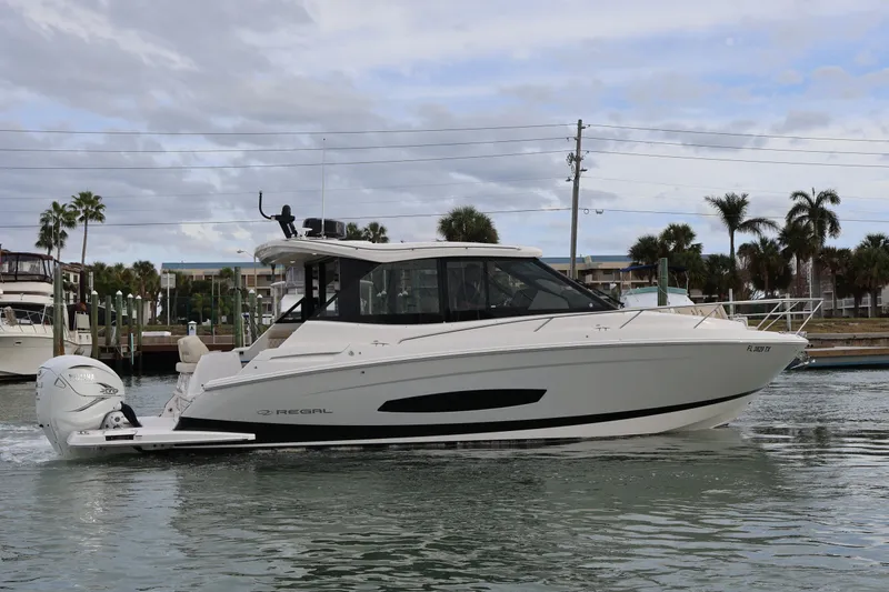  Yacht Photos Pics 2022 Regal 36 XO boat cruising on a calm waterway with palm trees in the background.