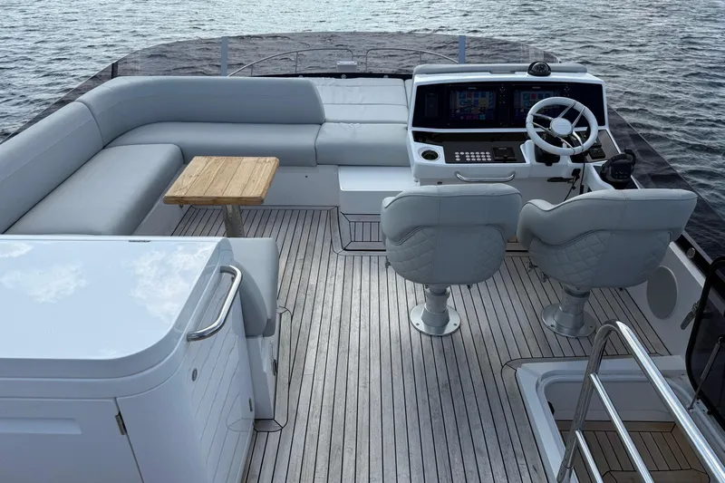  Yacht Photos Pics 2024 Sunseeker Manhattan 55 yacht deck with helm, seating, and table on water.