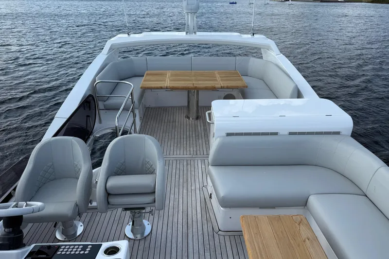  Yacht Photos Pics Luxurious 2024 Sunseeker Manhattan 55 yacht deck with seating and table, overlooking serene waters.