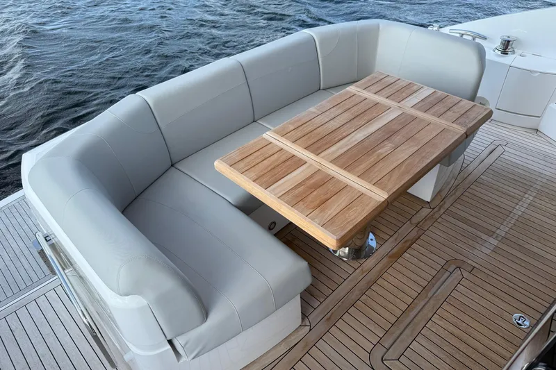 Yacht Photos Pics Luxurious seating area on 2024 Sunseeker Manhattan 55 yacht with wooden table and cushioned seats.
