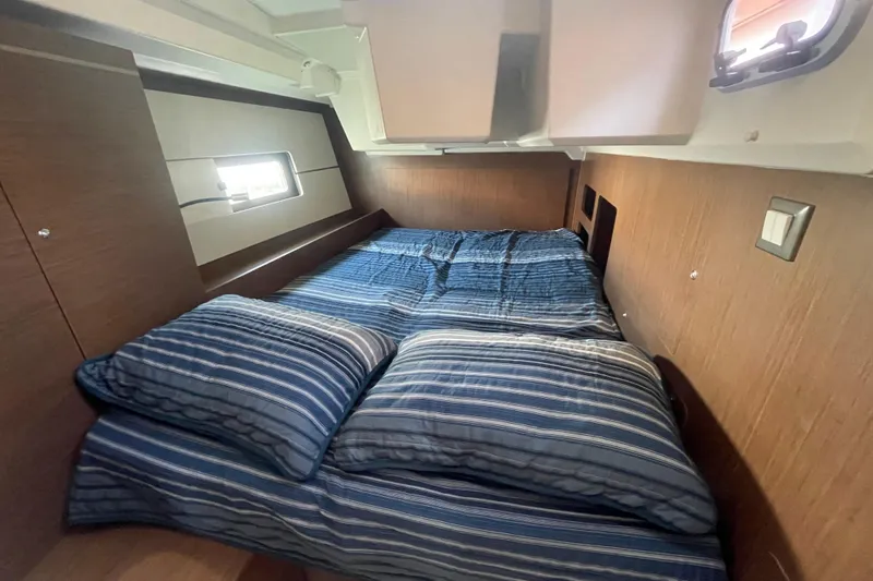 Dire Wolf Yacht Photos Pics Cozy cabin interior of 2020 Beneteau Oceanis 46.1 with striped bedding and wooden accents.