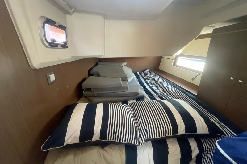 Dire Wolf Yacht Photos Pics Cozy cabin interior of 2020 Beneteau Oceanis 46.1 with striped bedding and cushions.