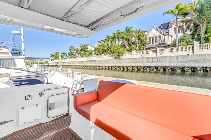  Yacht Photos Pics 2020 Sealine C390 yacht with red seating, docked near waterfront homes and palm trees.