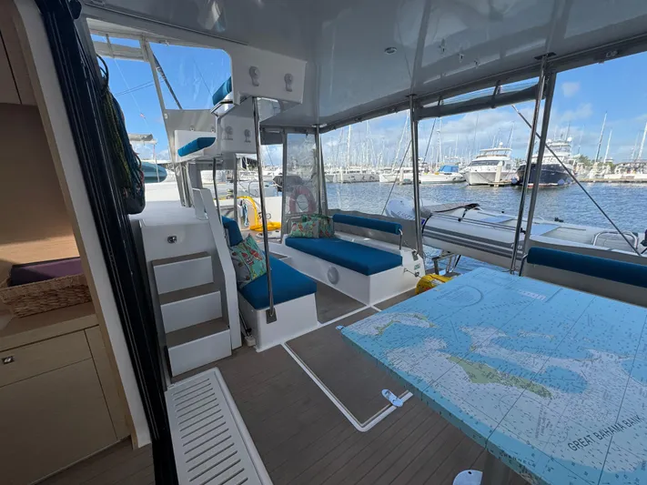 Encantado Yacht Photos Pics Interior of 2023 NEEL 47 trimaran with seating, map table, and marina view.