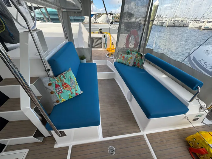 Encantado Yacht Photos Pics NEEL 47 yacht interior with blue seating, colorful pillows, and marina view, 2023 model.