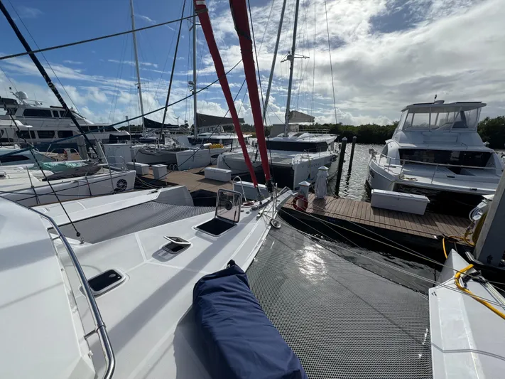 Encantado Yacht Photos Pics NEEL 47 trimaran docked at marina, surrounded by other boats, under partly cloudy sky.
