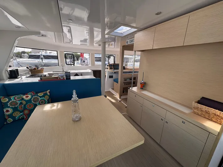 Encantado Yacht Photos Pics Modern NEEL 47 yacht interior with dining area, blue seating, and wooden cabinetry, 2023 model.