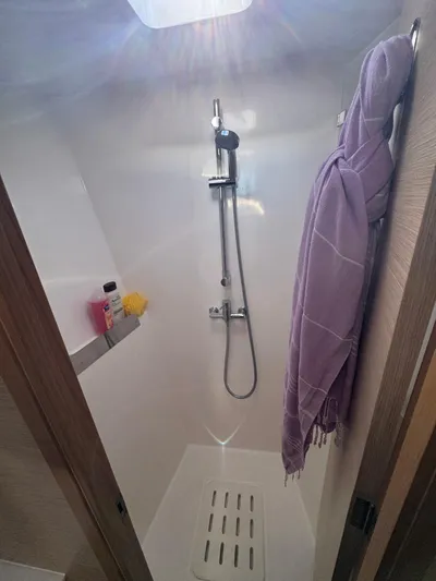 Encantado Yacht Photos Pics Modern shower in NEEL 47 yacht, 2023 model, with sleek design and purple towel.