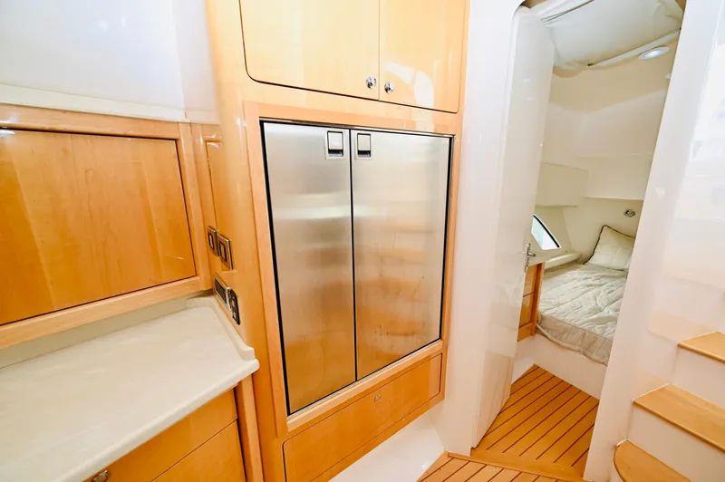  Yacht Photos Pics 2019 Intrepid 475 Sport Yacht interior with wood cabinetry and stainless steel fridge.