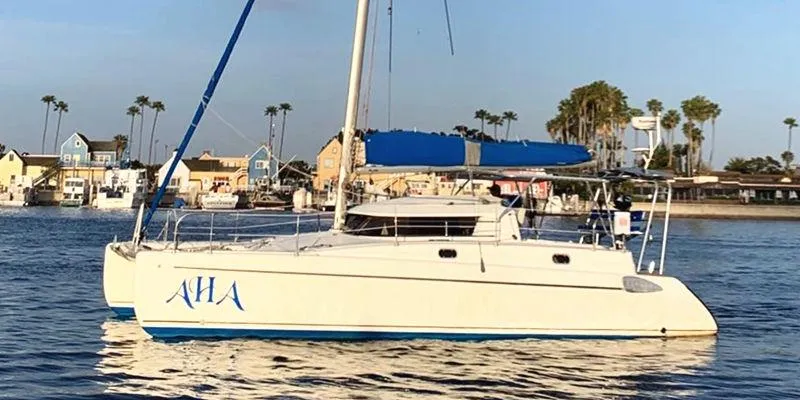 Aha Yacht Photos Pics 1997 Fountaine Pajot Tobago 35 catamaran sailing near coastal homes and palm trees.