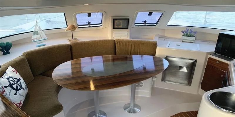 Aha Yacht Photos Pics Interior of 1997 Fountaine Pajot Tobago 35 catamaran with cozy seating and wooden table.