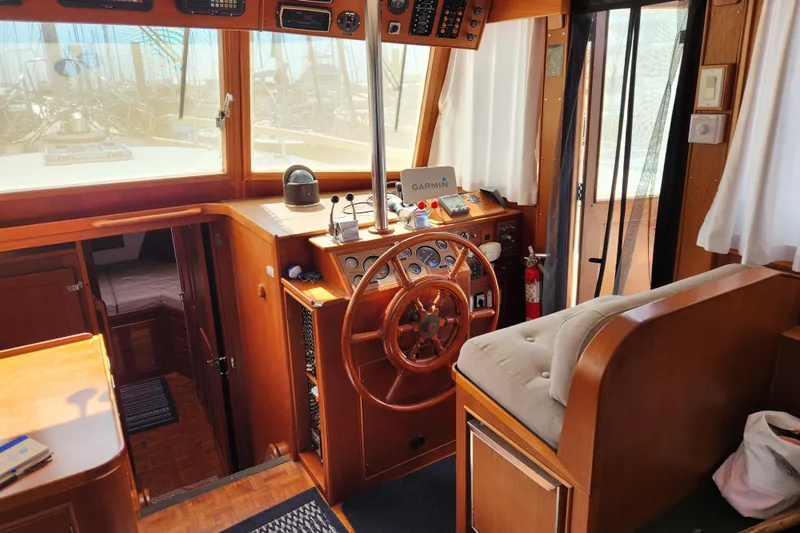 Part Of The Plan Yacht Photos Pics 1990 Grand Banks 46 Classic yacht interior with wooden helm, navigation equipment, and cozy seating.