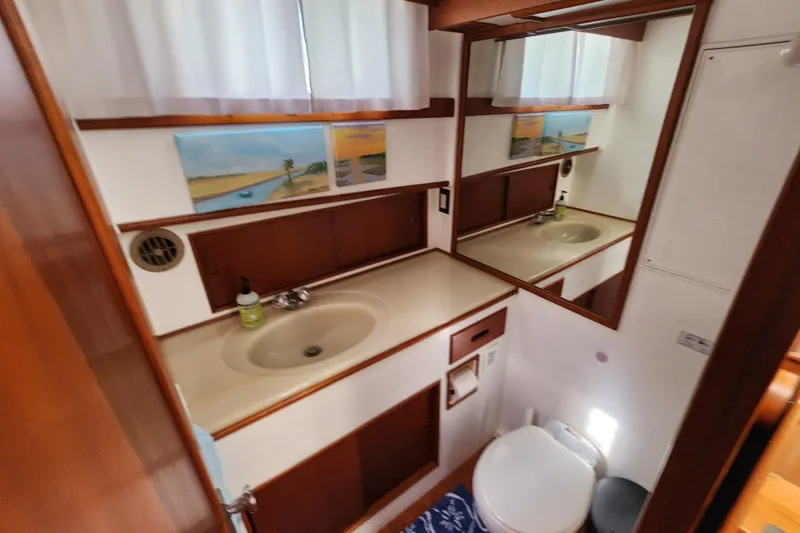 Part Of The Plan Yacht Photos Pics Bathroom interior of 1990 Grand Banks 46 Classic yacht with sink, mirror, and artwork.