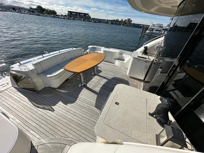 Mia Yacht Photos Pics 2009 Sea Ray 60 Sundancer yacht deck with seating and table, overlooking serene waterfront.