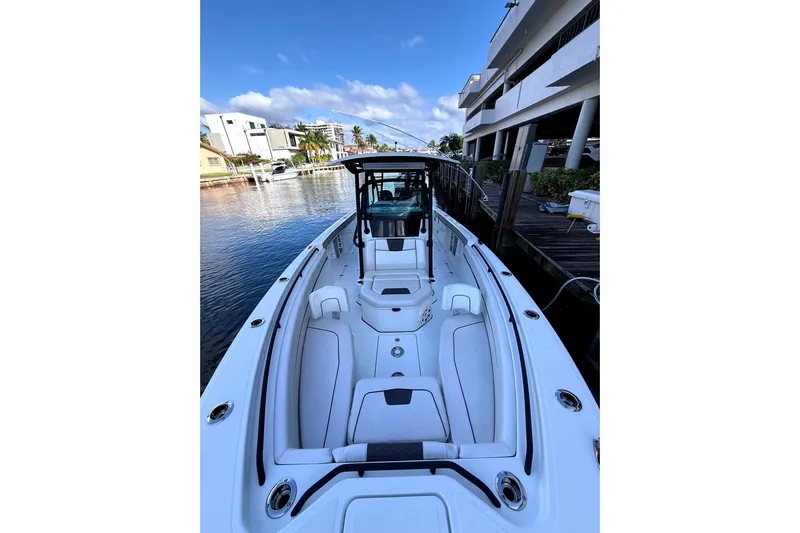  Yacht Photos Pics 2021 Wellcraft 302 Scarab boat docked by waterfront buildings under blue sky.