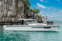 2022 Nimbus T11 boat cruising near rocky cliffs under a clear blue sky.